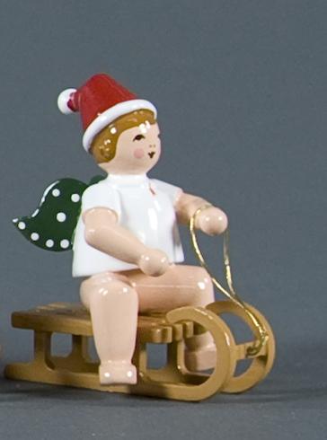 Weihnachtsengel auf Schlitten sitzend mit Mütze